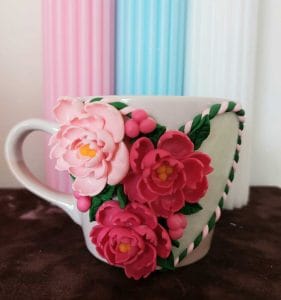 Imaginea reprezinta o cana decorata cu bujuroi lucrati handmade din lut polimeric. Este un buton care o gateroie unde se vor gasi toate canile cu flori in acesta categorie de cadouri deosebite.